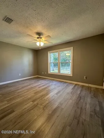an empty room with chandelier fan and windows