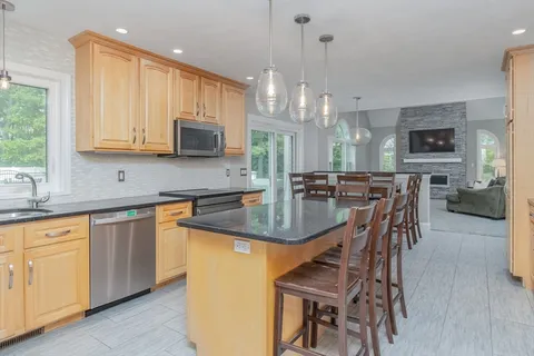 a kitchen with stainless steel appliances granite countertop a stove top oven a sink a dining table and chairs