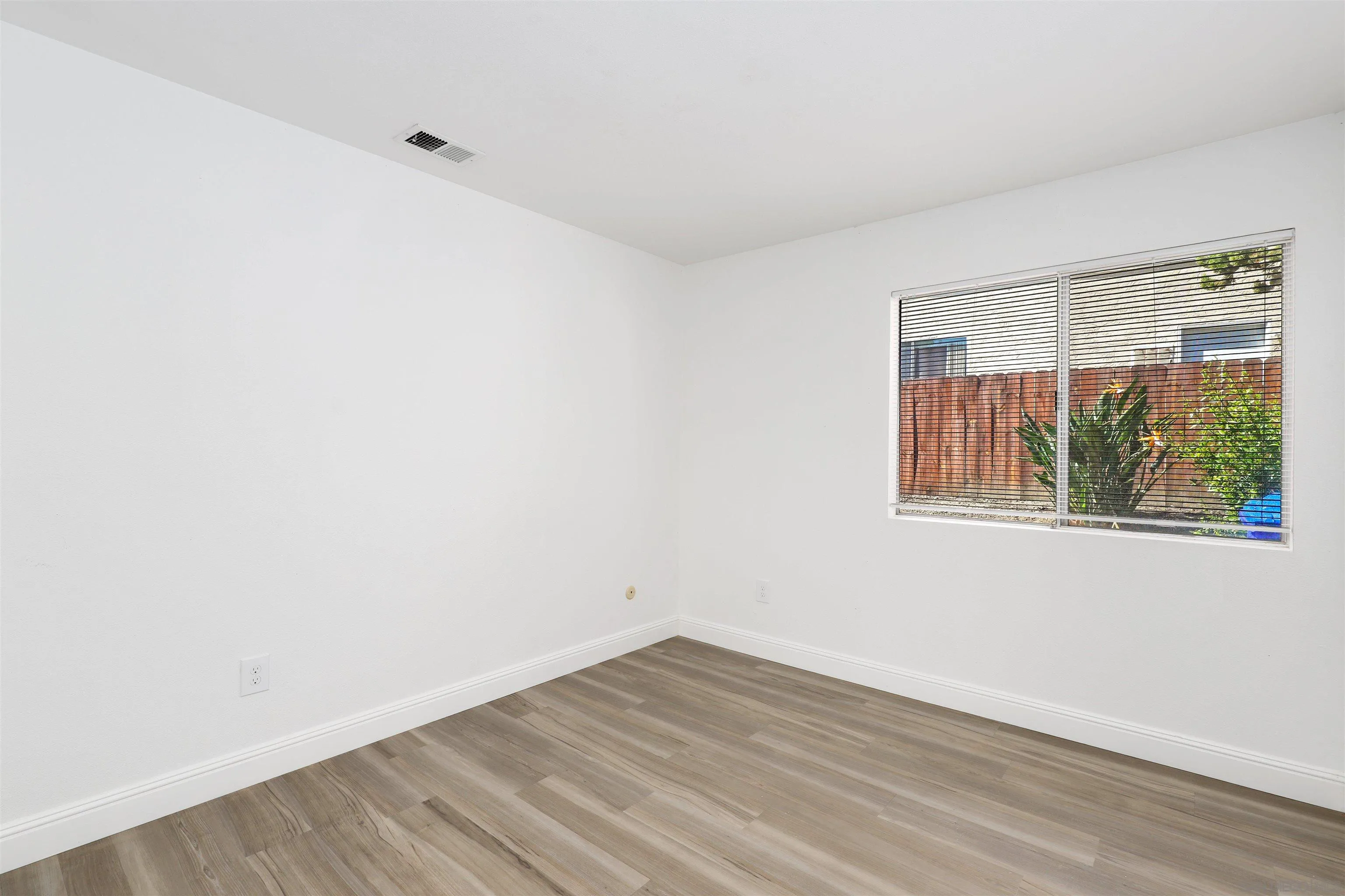 3933 Brown Street Oceanside, CA 92056 - Photo 19 of 25 an empty room with wooden floor and windows