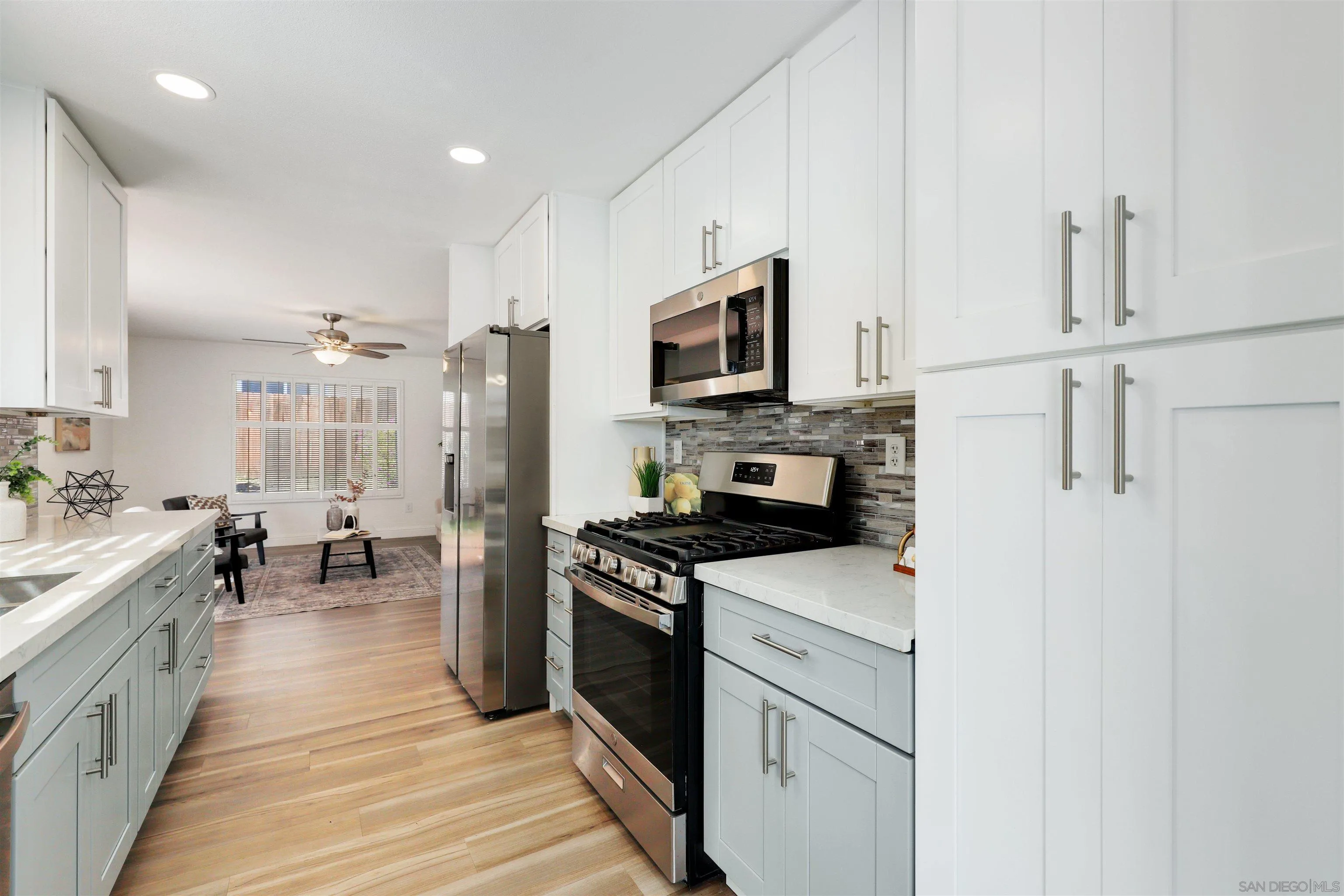 3933 Brown Street Oceanside, CA 92056 - Photo 8 of 25 a kitchen with stainless steel appliances a stove top oven a sink a refrigerator white cabinets and wooden floor
