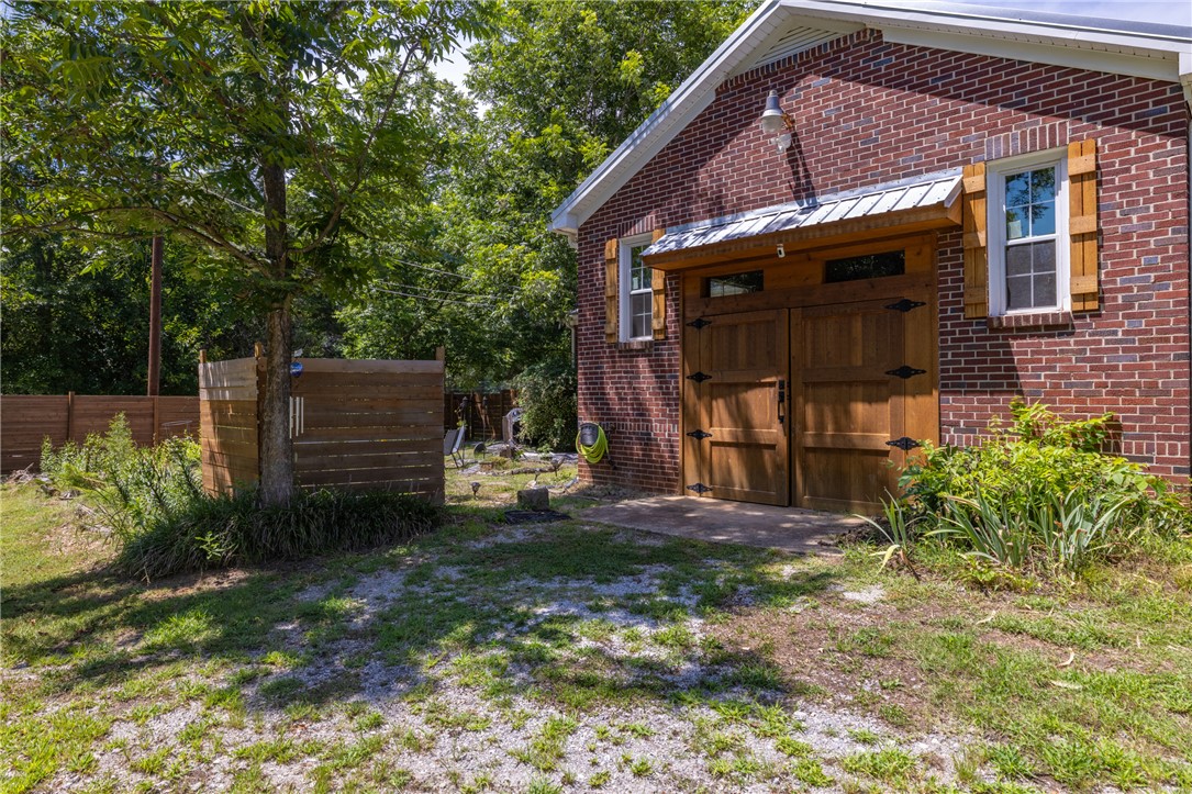 704 Cherry Street Pendleton, SC 29670 - Photo 22 of 28 A well-maintained brick structure features rich wooden garage doors and a lush green backdrop.