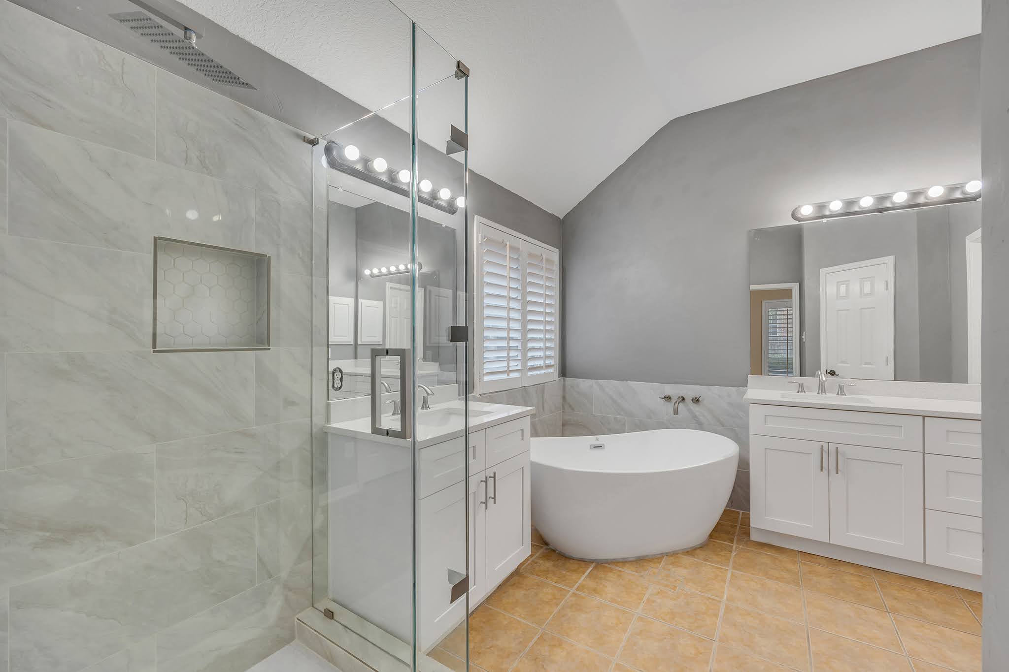 2726 Grimes Ranch Road Austin, TX 78732 - Photo 30 of 35 Full bath with two vanities, lofted ceiling, a freestanding bath, a shower stall, and light tile patterned floors