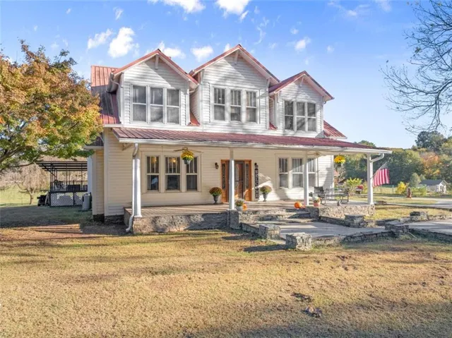 a view of a white house with a large pool and lawn chairs under a large tree
