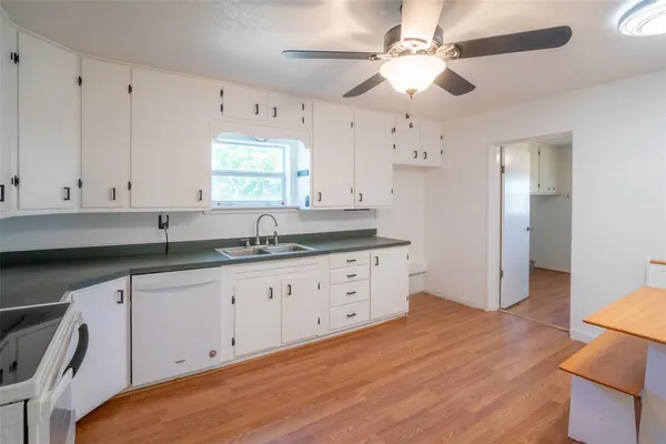 a kitchen with granite countertop white cabinets white countertops with a sink and a large window