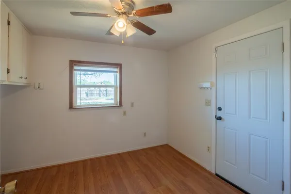 an empty room with wooden floor closet and windows