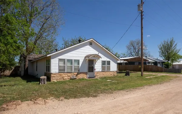 a front view of a house with a garden and trees