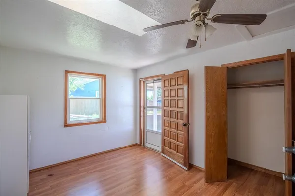 an empty room with wooden floor closet and windows
