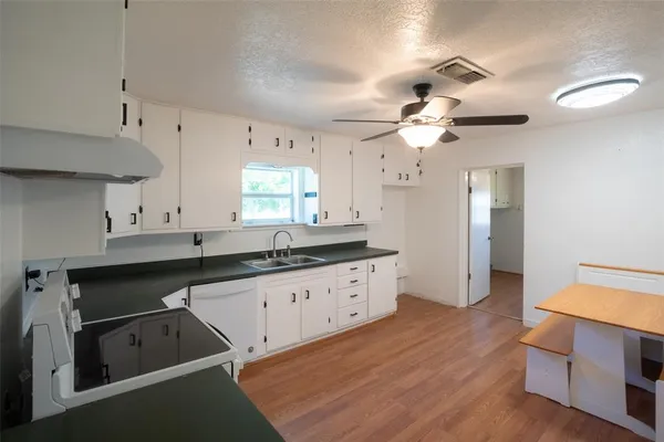 a kitchen with granite countertop a sink cabinets and wooden floor