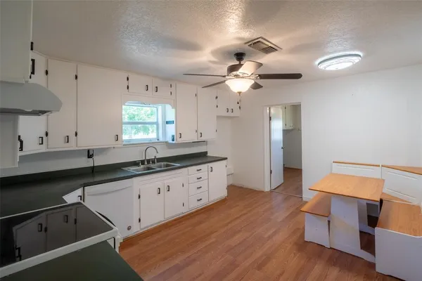 a kitchen with granite countertop a sink cabinets and wooden floor
