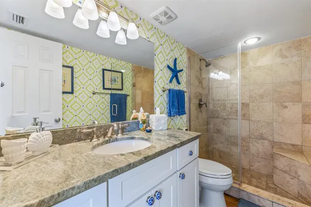 a bathroom with a granite countertop sink a toilet and a mirror