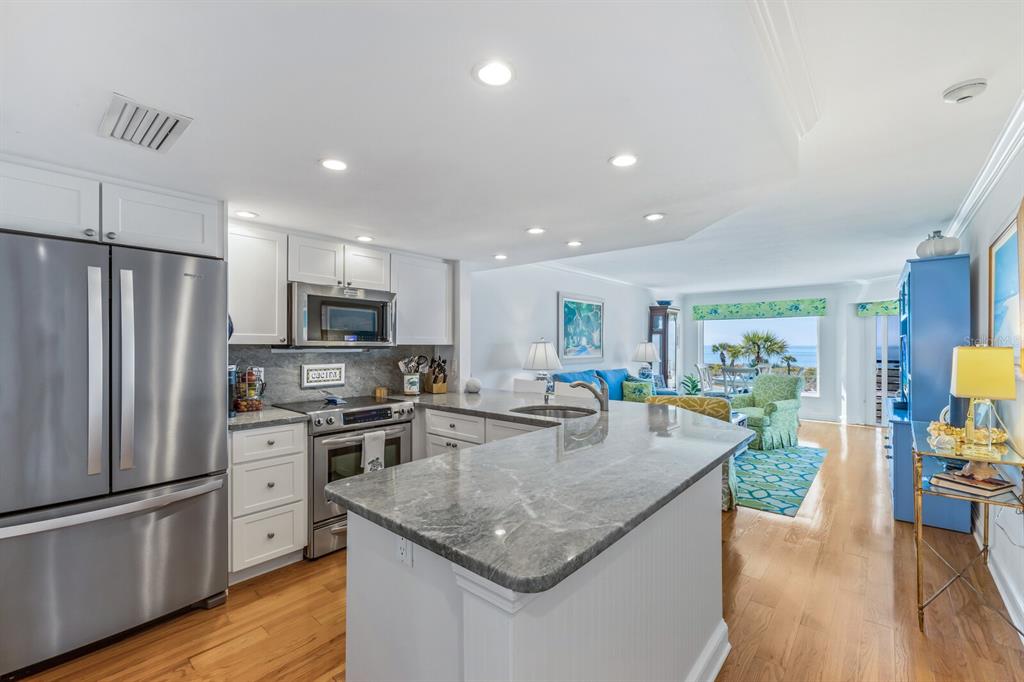 5000 Gasparilla Road, Unit BC204 Boca Grande, FL 33921 - Photo 5 of 36 a kitchen with stainless steel appliances granite countertop a refrigerator a stove top oven a sink dishwasher and white cabinets with wooden floor