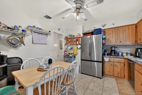 a kitchen with stainless steel appliances granite countertop a refrigerator a sink dishwasher a dining table and chairs with wooden floor