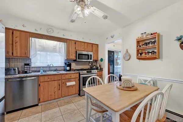 a kitchen with stainless steel appliances granite countertop a stove top oven a sink a dining table and chairs