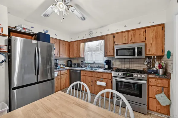 a kitchen with stainless steel appliances granite countertop a refrigerator a stove top oven a sink dishwasher and white cabinets with wooden floor
