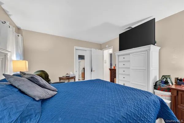 a bedroom with a bed and a flat tv screen on dresser