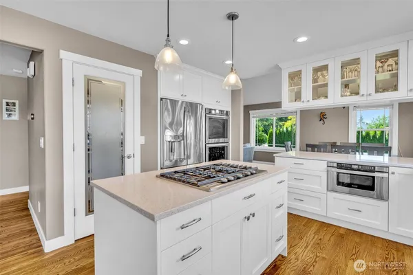 a kitchen with a stove a refrigerator a sink and white cabinets with wooden floor