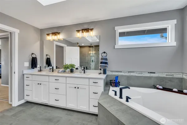 a bathroom with a tub a sink and mirror