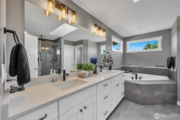 a bathroom with a double vanity sink a mirror and bathtub