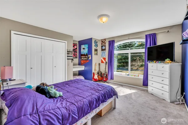 a bedroom with a bed and a flat tv screen on dresser