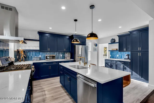 a kitchen with stainless steel appliances granite countertop a sink a stove and a refrigerator