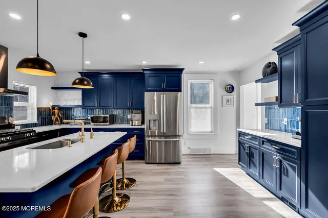 a kitchen with stainless steel appliances granite countertop a refrigerator a sink dishwasher a stove and a refrigerator