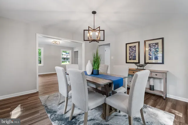 a dining room with wooden floor a chandelier a wooden table and chairs