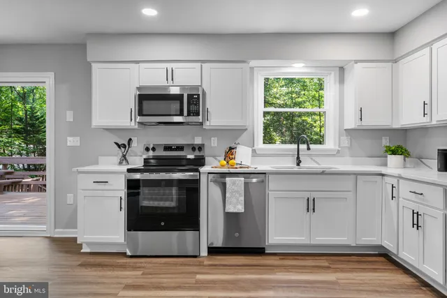 a kitchen with stainless steel appliances granite countertop a stove a sink and a microwave