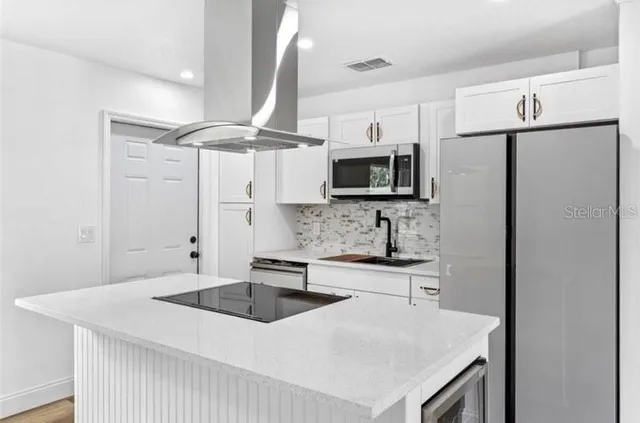 a kitchen with stainless steel appliances a sink a refrigerator a stove a microwave and island