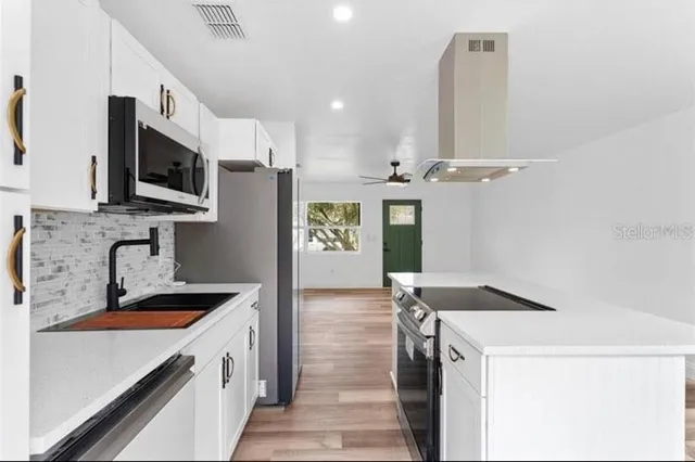 a kitchen with a sink a counter top space cabinets and stainless steel appliances