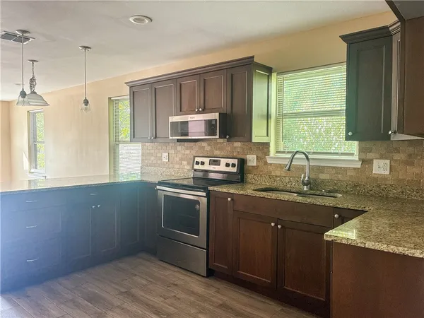 a kitchen with granite countertop a sink cabinets and stainless steel appliances