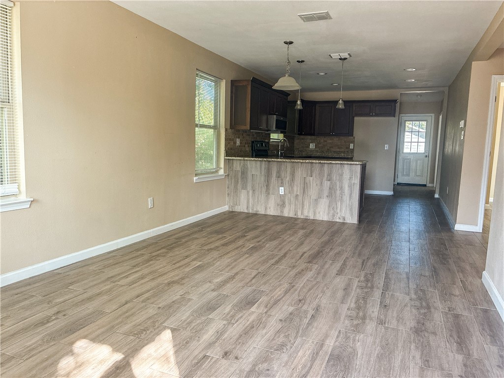 305 East Tullos Street Three Rivers, TX 78071 - Photo 6 of 13 an empty room with wooden floor and windows