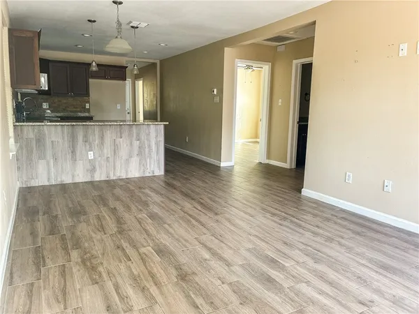 a view of a kitchen with kitchen island a sink wooden floor and a large window