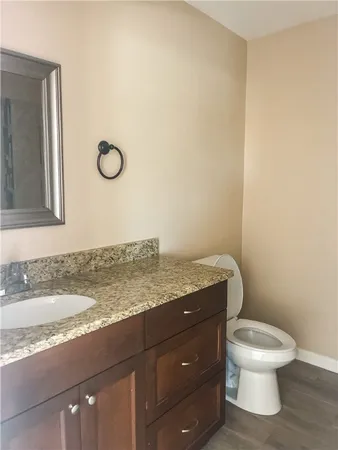 a bathroom with a granite countertop toilet and a sink