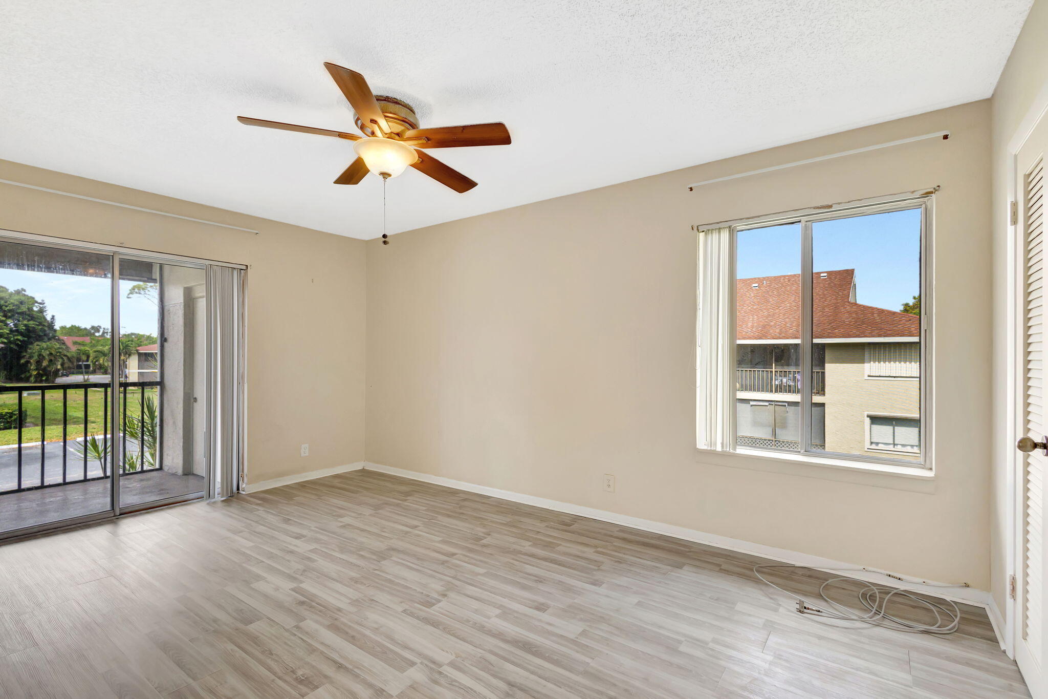 6458 Chasewood Drive, Unit E Jupiter, FL 33458 - Photo 13 of 33 an empty room with wooden floor fan and windows