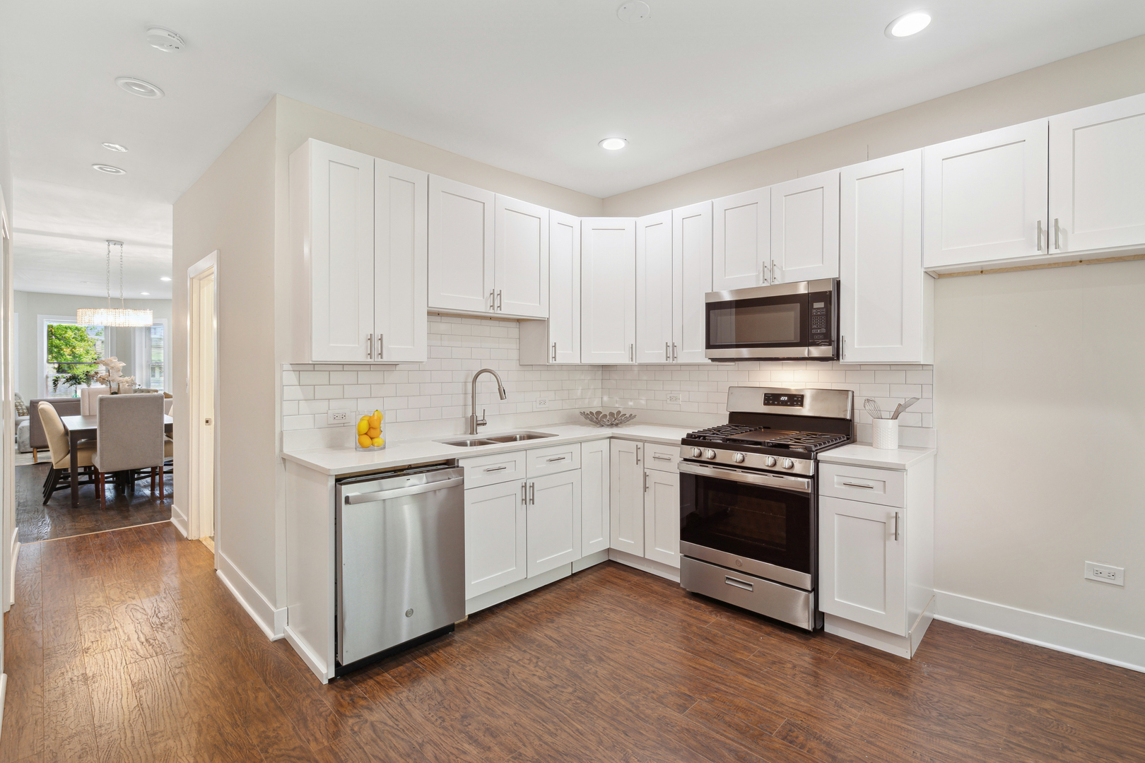 6826 South Prairie Avenue, Unit 1 Chicago, IL 60637 - Photo 9 of 20 a kitchen with stainless steel appliances granite countertop a stove top oven a sink a refrigerator white cabinets and wooden floor