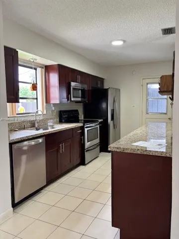 a kitchen with kitchen island granite countertop a sink stainless steel appliances and cabinets