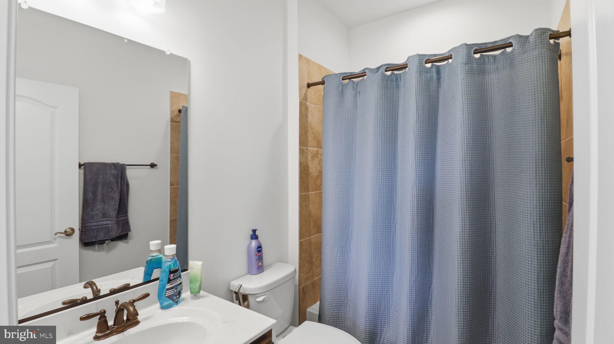 11502 Aden Road Nokesville, VA 20181 - Photo 89 of 106 a bathroom with a shower curtain a sink and a toilet