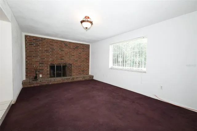 an empty room with windows and fireplace