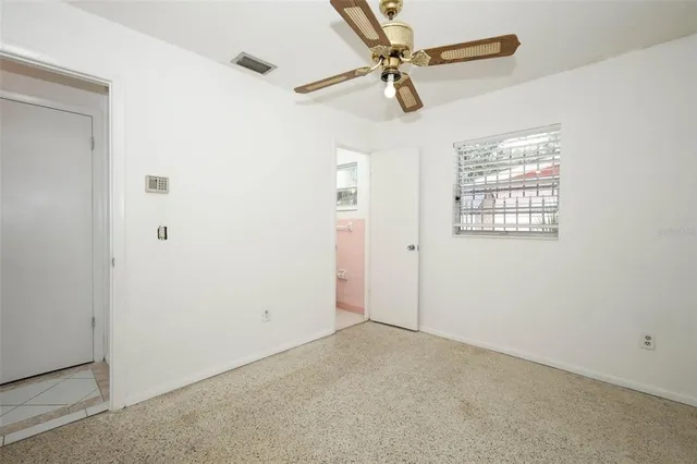 an empty room with windows and fan