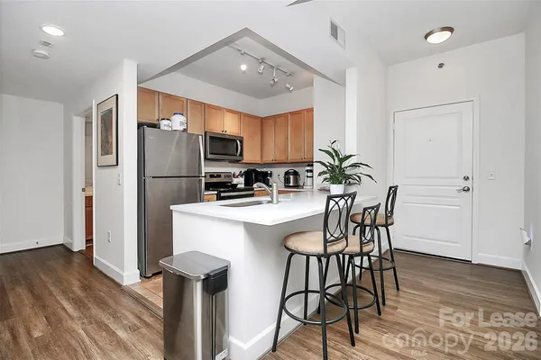 a kitchen with stainless steel appliances a dining table chairs refrigerator and sink