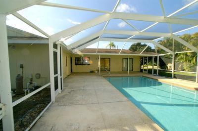1683 Northwest Spruce Ridge Drive Stuart, FL 34994 - Photo 8 of 23 a view of a patio with table and chairs under an umbrella