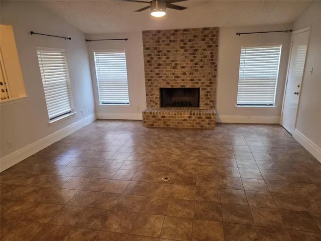 an empty room with windows and fireplace