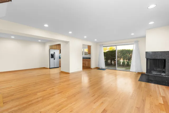 a view of an empty room with wooden floor and a fireplace