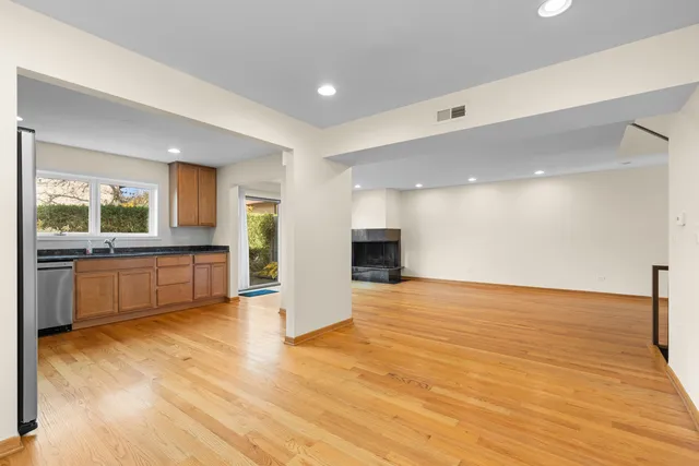 a view of an empty room with kitchen view and a window