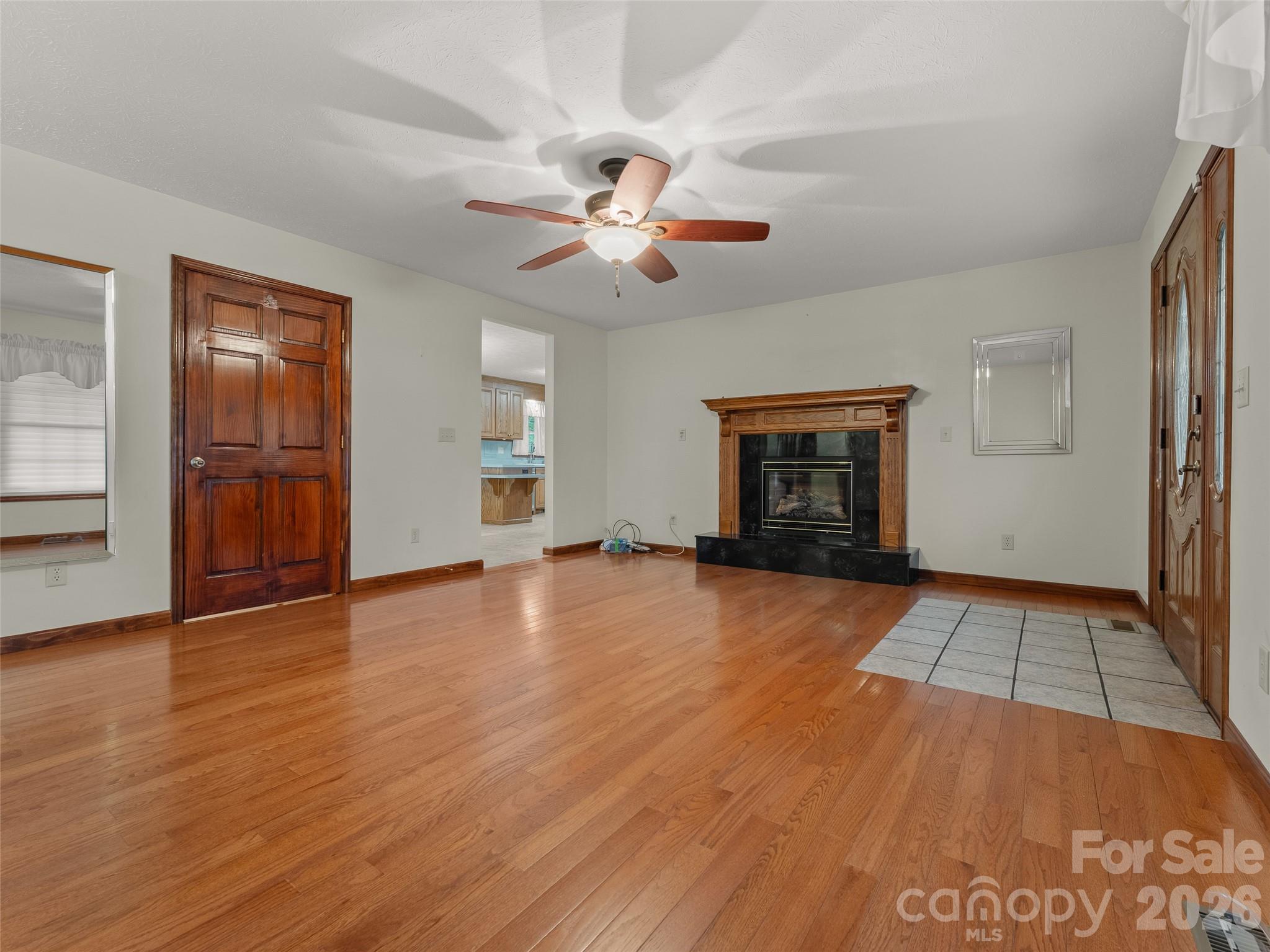 476 Jackson Loop Road Flat Rock, NC 28731 - Photo 3 of 34 an empty room with wooden floor chandelier fan and windows
