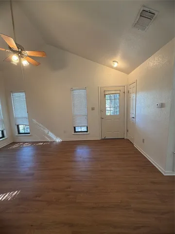 a view of empty room with wooden floor and fan