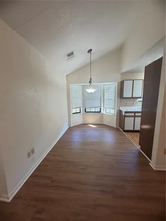 a view of empty room with wooden floor and window