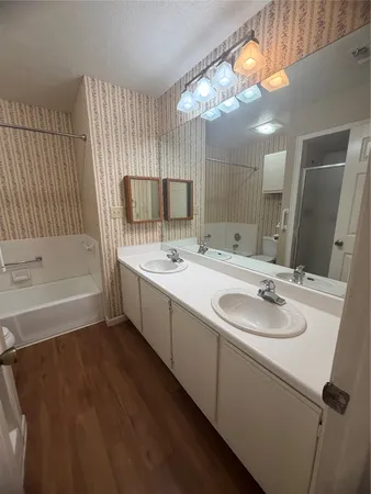 a bathroom with a double vanity sink a mirror and a bathtub