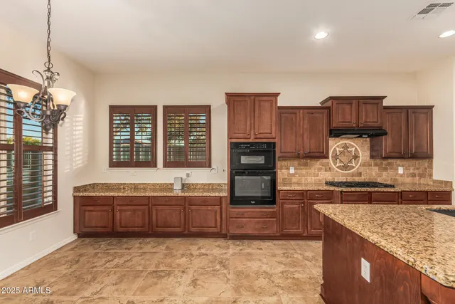 a kitchen with stainless steel appliances granite countertop a kitchen island a stove and a sink
