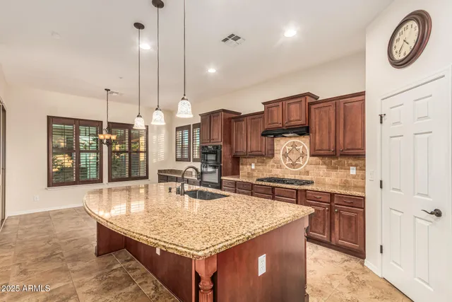a kitchen with granite countertop a sink a counter top space and cabinets